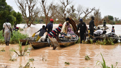 This photograph take on 20 August, 2024 shows locals preparing canoes to carry people following heavy rains that damaged National Road 25 from the Nigerien capital Niamey to the provinces of Tillabéri and Tahoua in western Niger.