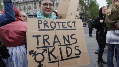 Um manifestante segura um cartaz com a frase “Protect trans kids” (Proteja as crianças trans) durante uma manifestação contra a transfobia e os ataques transfóbicos na Place de la République, em Paris, em 5 de maio de 2024.