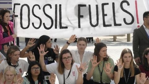 Activists demonstrate with a sign that reads "fossil fuels" at the COP28 U.N. Climate Summit, Tuesday, Dec. 12, 2023, in Dubai, United Arab Emirates.