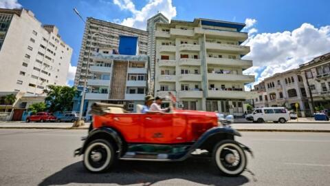 O mașină de epocă trece prin fața unui imobil de locuințe din cartierul Vedado, Havana, 1 octombrie 2024.