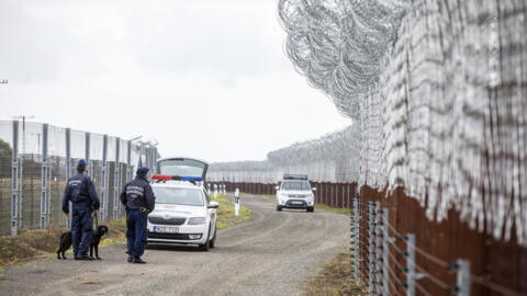 Policiais húngaros patrulham ao longo de uma estrada onde uma barreira de segurança foi construída na fronteira entre a Hungria e a Sérvia, perto de Roszke, Hungria, em 6 de junho de 2023.