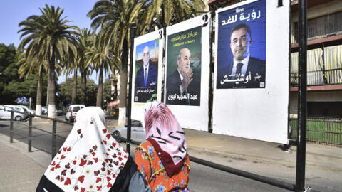 Women walk past electoral banners of presidential candidates in Algiers, Algeria, on 27 August 2024.