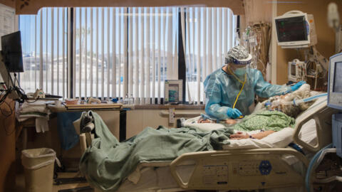Uma enfermeira no leito de um paciente com coronavírus em uma unidade de terapia intensiva no Providence St. Mary's Medical Center em Apple Valley, Califórnia, em 11 de janeiro de 2021. 