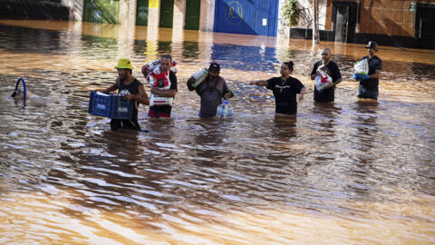 Pessoas caminham por uma área inundada por fortes chuvas em Porto Alegre, no Rio Grande do Sul, Brasil, segunda-feira, 6 de maio de 2024.