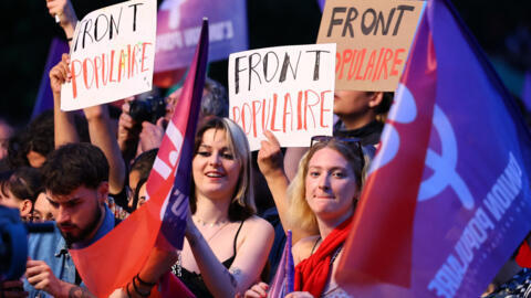 Personas sostienen pancartas en apoyo del Nuevo Frente Popular en una manifestación contra el partido de extrema derecha Reagrupamiento Nacional en París en la noche de la primera vuelta de las elecciones anticipadas.