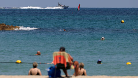 Des gens regardent un navire de la marine israélienne naviguer en Méditerranée, au milieu des hostilités entre le Hezbollah et Israël, au large de Haïfa, Israël, le 6 août 2024.