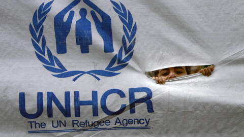 تصویری از یک کودک بی‌خانمان در کنار لوگوی آژانس پناهندکان سازمان ملل