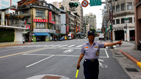 2024 年 7 月 23 日，台湾台北，一名交警在空旷的道路上做手势，人们参加一年一度的防空演习，演习期间民众被要求在室内待 30 分钟。