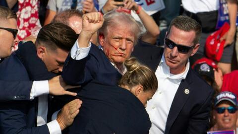 Republican candidate Donald Trump is seen with blood on his face surrounded by Secret Service agents as he is taken off the stage