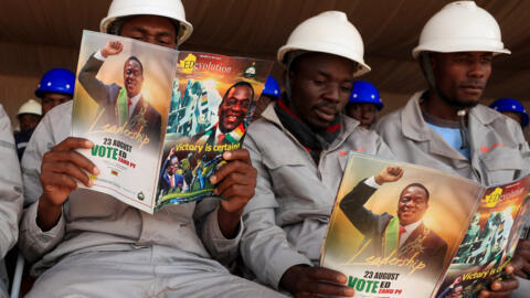 Workers read magazines with pictures of Zimbabwe's President Emmerson Mnangagwa, as he commissions the Prospect Lithium mine and processing plant in Goromonzi, Zimbabwe 5 July, 2023. 