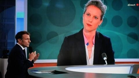 This photograph shows a television screen broadcasting France's President Emmanuel Macron addressing a live interview as a portrait of Lucie Castets, the 'Nouveau Front Populaire' choice for Prime Min