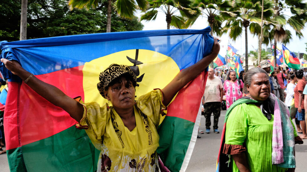 A woman carries a flag of the Socialist Kanak National Liberation Front (FLNKS) during a demonstration against the enlargement of the electorate for the forthcoming provincial elections in New Caledon