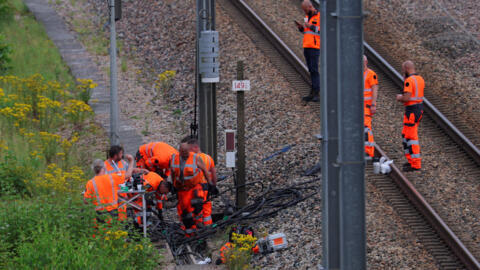 Des cheminots de la SNCF et des agents des forces de l'ordre travaillent sur le site où des vandales ont attaqué le réseau français de trains à grande vitesse par une série d'actions coordonnées qui ont entraîné d'importantes perturbations avant la cérémonie d'ouverture des Jeux olympiques de Paris 2024, à Croisilles, dans le nord de la France, le 26 juillet 2024.