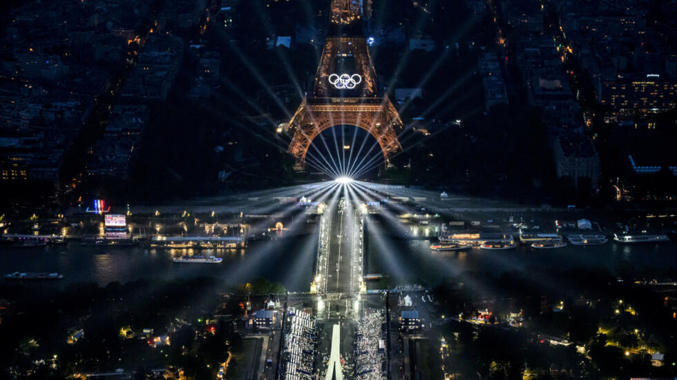 Vue aérienne de la tour Eiffel et des anneaux olympiques illuminés lors de la cérémonie d'ouverture des Jeux Olympiques de Paris 2024.