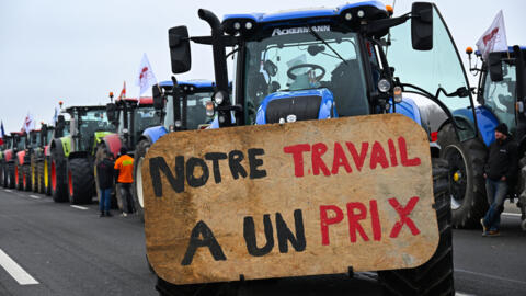 Un tracteur affiche une banderole sur laquelle on peut lire « notre travail a un prix », alors que des agriculteurs venant de Meuse et de Moselle bloquent l'autoroute A4 près de Jossigny, à l'est de Paris, le 30 janvier 2024.