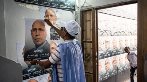 A supporter of Mauritanian President Mohamed Ould Ghazouani puts up a poster at a campaign headquarters in downtown Nouakchott on 25 June, 2024.