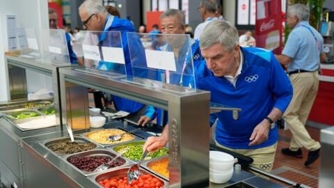 IOC President Thomas Bach samples some food at a salad bar at the Olympic Village in Saint-Denis, outside Paris, on 22 July 2024.