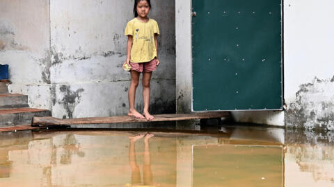 This photo taken on July 28, 2024 shows a girl standing outside her home in front of flood waters in Ben Voi village on the outskirts of Hanoi Hundreds of people in the suburbs of Hanoi have been livi