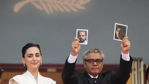 ADDING IDs OF PEOPLE IN PHOTOGRAPHS Director Mohammad Rasoulof holds up photographs of actors Soheila Golestani, right, and Missagh Zareh alongside Soheila Golestani, left, upon arrival at the premier