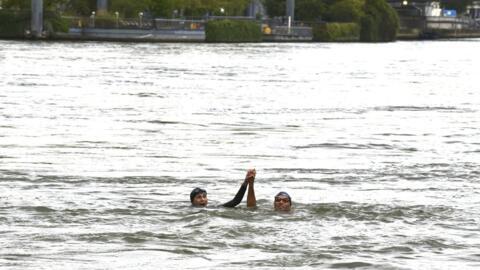 France's Minister of Sports and the Olympic and Paralympic Games Amelie Oudea-Castera and Paralympics triathlon champion Alexis Hanquinquant swim in the River Seine in Paris, on 13 July 2024.