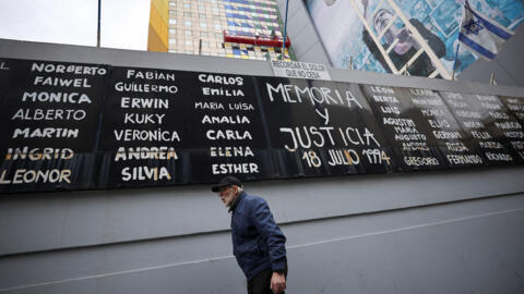 Un hombre pasa junto a una pancarta en la que se lee "Memoria y justicia" con los nombres de las víctimas del atentado de 1994 contra el centro comunitario de la Asociación Mutual Israelita Argentina (AMIA).