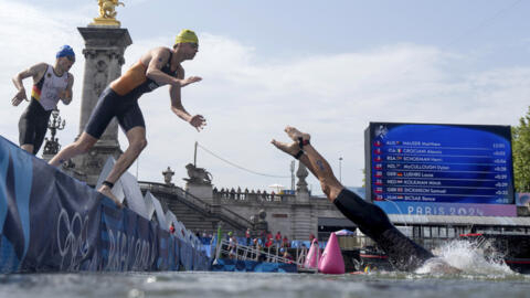 New Zealand's Dylan McCullough, right, dives back into the water followed by the Netherland's Mitch Kolkman for the second lap of the swim portion at the men's individual triathlon competition at the