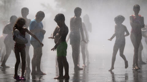 Children cool off in water fountains during a heatwave in Madrid, Spain.