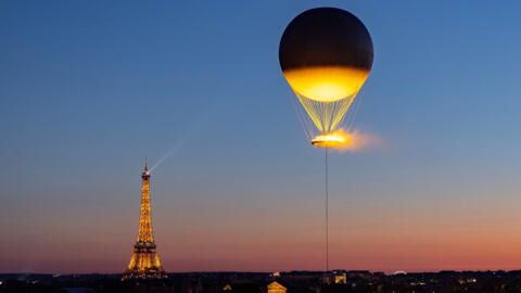 The Olympic cauldron and the Eiffel Tower are seen from the Musée des Arts Decoratifs after sunset 