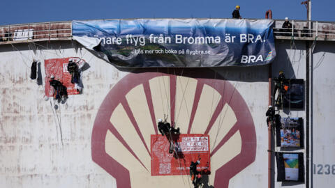 Greenpeace activists climb a storage tank to hang a banner and glue posters denouncing the Dutch oil company Shell at the company's refinery in the port of Rotterdam on 4 October, 2021.