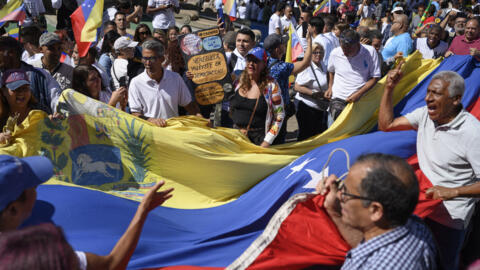 Simpatizantes de la líder de la oposición venezolana, María Corina Machado, sostienen una bandera nacional durante una manifestación en el aniversario del levantamiento de 1958 que derrocó a una dictadura militar, en la plaza Altamira de Caracas el 23 de enero de 2024.