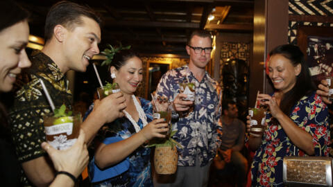 In this photo taken Friday, Sept. 26, 2014, a group of people wearing Hawaiian shirts and dresses drink Mai Tais to celebrate the 70th anniversary of the Mai Tai at Trader Vic's in Emeryville, Calif.