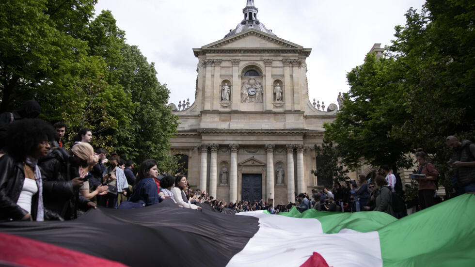 Manifestantes com bandeira da Palestina diante do prédio da Sorbonne, em Paris.