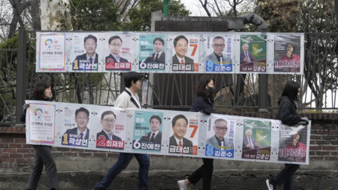 Officials from the election management committee carry posters showing candidates before placing on the wall, in Seoul, South Korea, Thursday, March 28, 2024. Official campaigning kicked off Thursday for the April 10 general elections, with the ruling People Power Party (PPP) and the main opposition Democratic Party (DP) vying fiercely for control of the National Assembly, Yonhap news agency reported. (AP Photo/Ahn Young-joon)