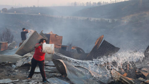 Moradora tenta apagar incêndio que destruiu sua casa em Valparaíso, nesta segunda-feira 2 de janeiro de 2017.