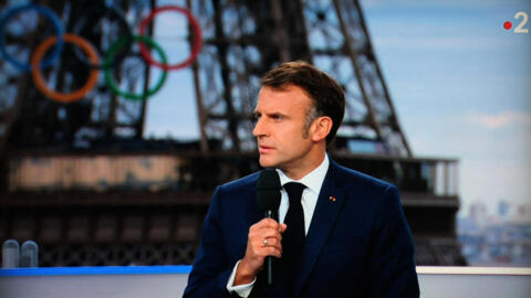 President Emmanuel Macron addressing a live interview on French TV on a set installed on the roof of the Musee de l'Homme  at the Trocadero, Paris, with the Olympics rings seen in the background.