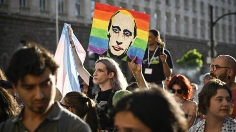 A protester holds a portrait of Russia's President Vladimir Putin against a Rainbow flag during a demonstration against a new law banning LGBTQ+ "propaganda" in schools in Bulgaria, in Sofia on 7 August, 2024.