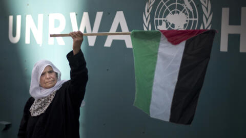 O femeie ține un steag palestinian în timpul unei demonstrații în fața sediului UNRWA pentru a protesta împotriva reducerii ajutorului alimentar pentru refugiații palestinieni, 9 octombrie 2019 în Gaza