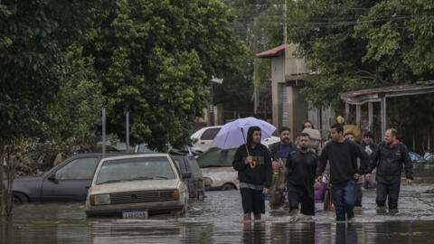 Moradores atravessam ruas alagadas de Canoas (RS) - o aquecimento global foi um dos fatores que favoreceram enchentes históricas na região (14//04/24).