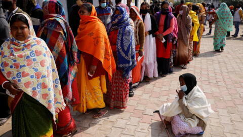 People stand in a queue to cast their vote outside a polling station in the town of Vrindavan, in the northern state of Uttar Pradesh, India, on 10 February 2022. 