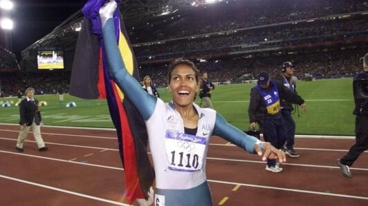 L'athlète Cathy Freeman fêtant sa victoire sur 400m aux Jeux olympiques de Sydney, le 25 septembre 2000, en brandissant les drapeaux australien et aborigène.