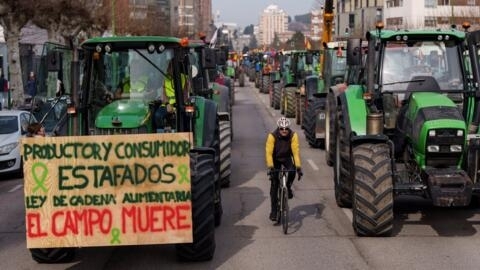 Des agriculteurs espagnols conduisent leur tracteur portant une pancarte indiquant « Producteurs et consommateurs escroqués, loi sur la chaîne alimentaire, la campagne se meurt » lors d'une manifestation réclamant des conditions équitables pour le secteur agricole, à Burgos, dans le nord de l'Espagne, le 6 février 2024.