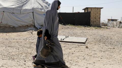 A woman walks with a child at a camp for people affiliated with the Islamic State in Syria near the border with Turkey in 2018. 