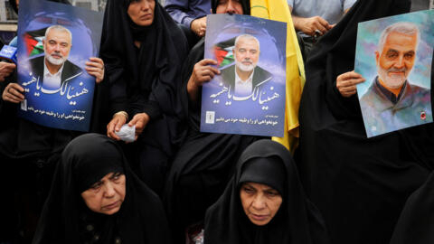 Iranians hold posters of assassinated Hamas chief, Ismail Haniyeh during his funeral procession, in Tehran, Iran, 1 August 2024. 