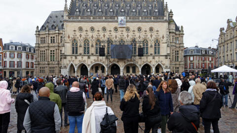 Local residents attend the funeral ceremony for French schoolteacher Dominique Bernard broadcasted on a giant screen on the facade of the town hall in Arras, northern France, on October 19, 2023.