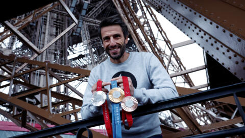巴黎奥运奥组委主席埃斯唐盖在铁塔手持金银铜牌。