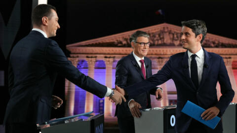 French far-right Rassemblement National (RN) party President and lead MEP Jordan Bardella (L) and French Prime Minister Gabriel Attal (R) shake hands in front of First Secretary of the French left-win