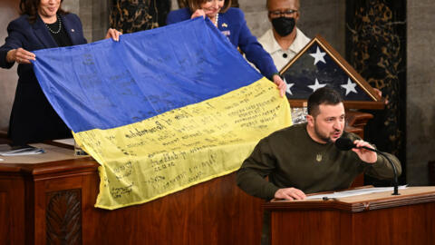 Le président ukrainien Volodymyr Zelensky s'exprime après avoir remis un drapeau national ukrainien à la présidente de la Chambre des représentants des États-Unis Nancy Pelosi et à la vice-présidente américaine Kamala Harris (à gauche) lors de son discours devant le Congrès américain au Capitole des États-Unis à Washington, DC, le 21 décembre 2022.