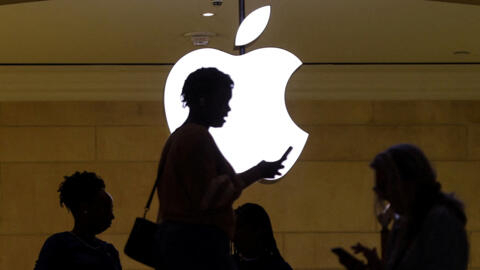 Uma mulher utilisa um celular diante de um logotipo da Apple, em Nova York, em 14/04/23.