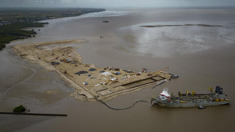 A ship creates an artificial island by extracting offshore sand to create a coastal port for offshore oil production at the mouth of the Demerara River in Georgetown, Guyana, April 12, 2023. Guyana op