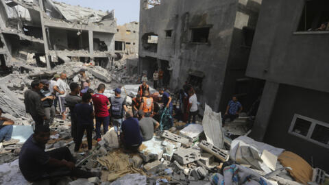 2024 年 5 月 19 日，星期日，加沙地带，努塞拉特难民营，以色列袭击了一栋居民住宅，据报20人死亡。巴勒斯坦人看着被毁的建筑。(美联社照片/Ismael Abu Dayyah）